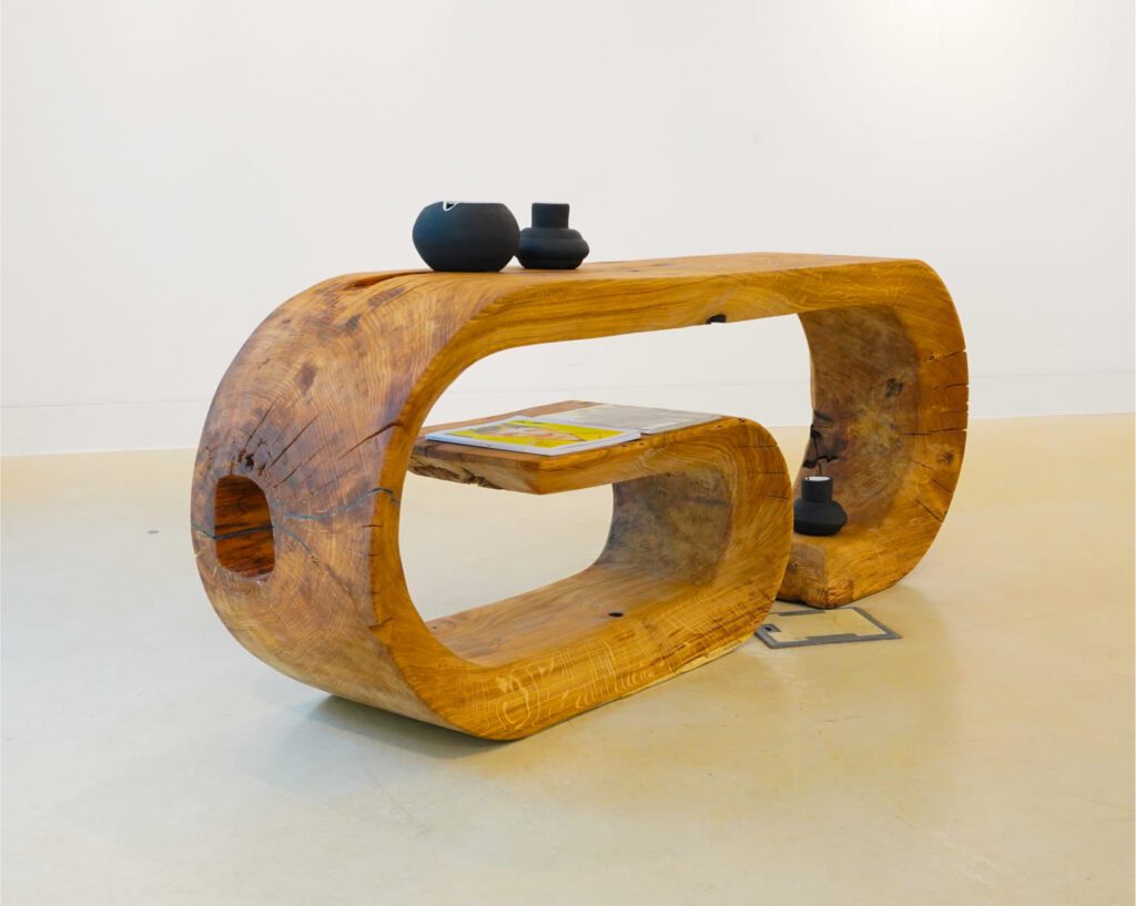 Oze sculptural wooden commode with natural cracks and integrated shelving in gallery space