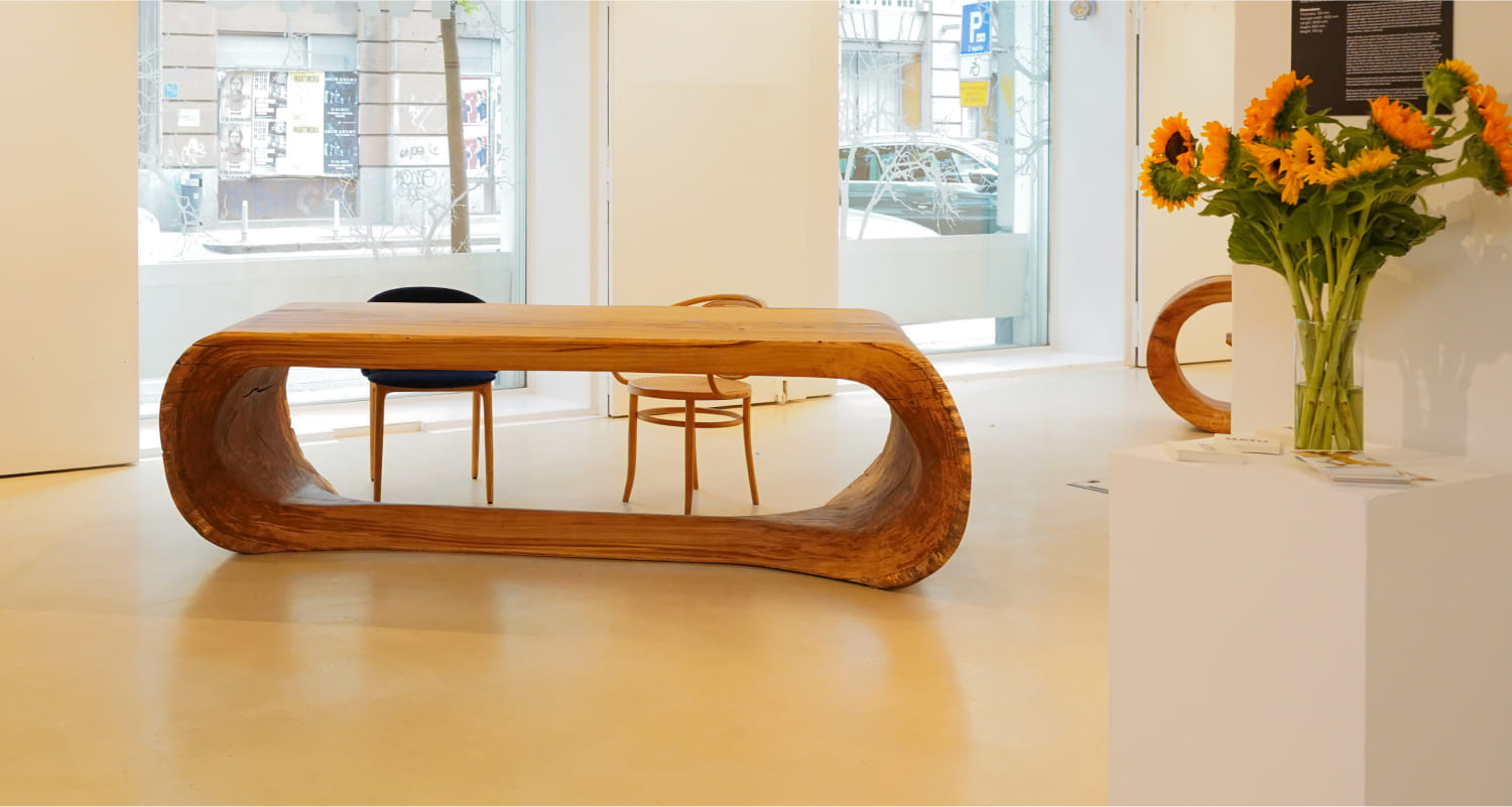 OZE sculptural solid wood table displayed in contemporary gallery interior