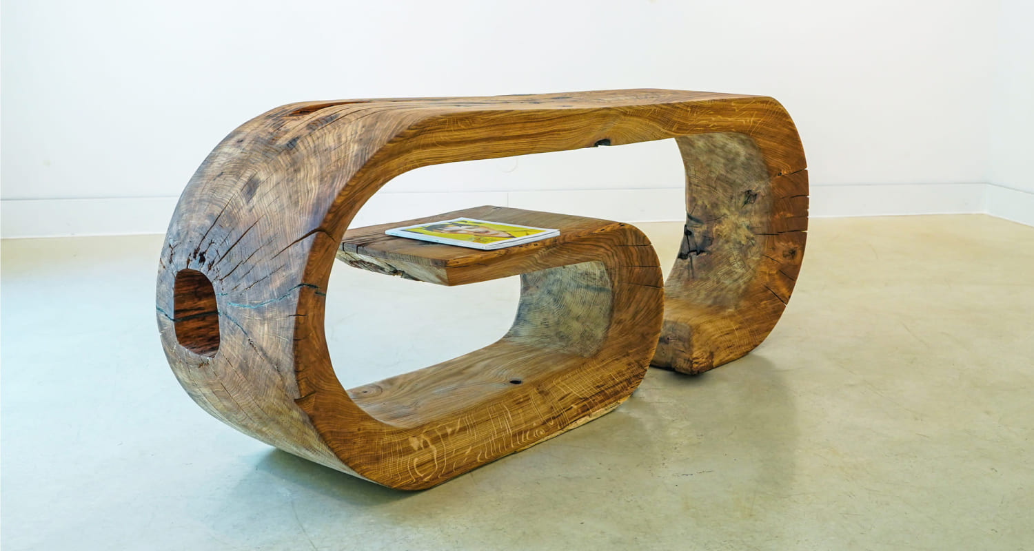 OZE sculptural wooden commode with integrated floating shelf holding a tablet in a white gallery setting